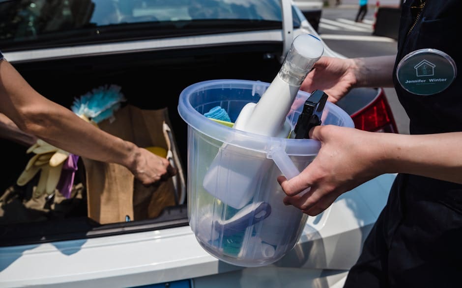 Close-up of cleaning supplies in a bucket near a car trunk, outdoors.