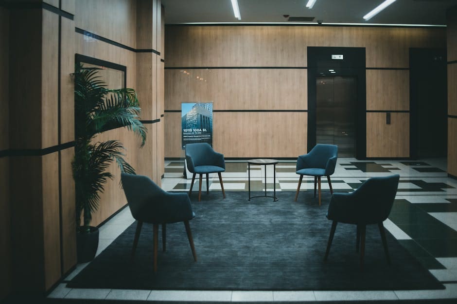 A stylish office lobby featuring chic chairs and a minimalistic design with a neutral tone.