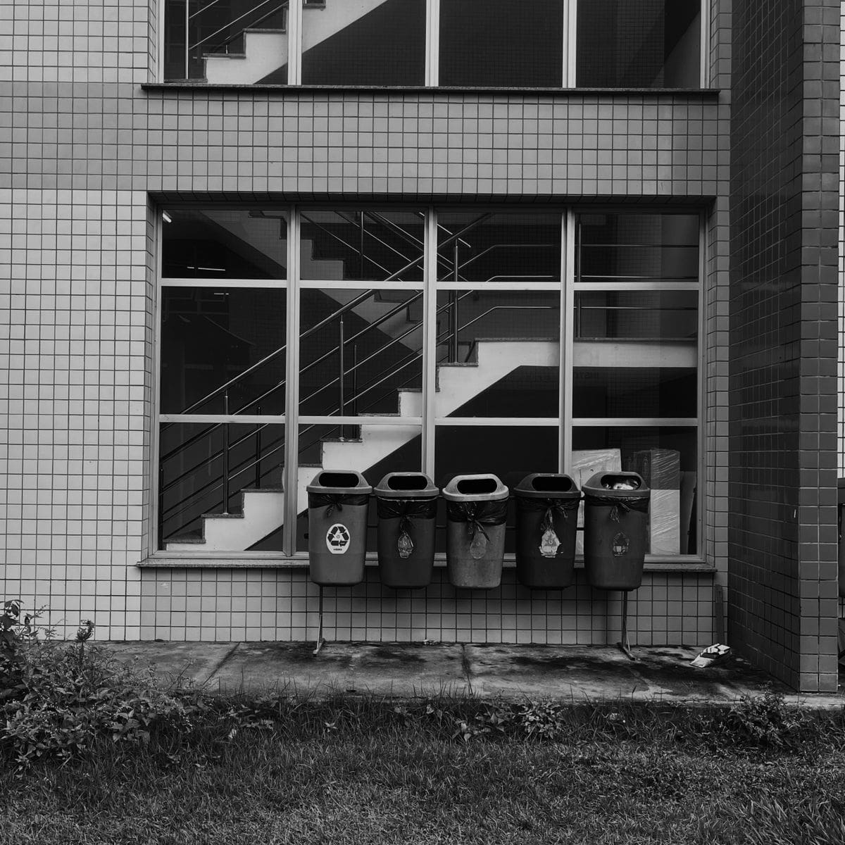 Bacs de recyclage devant la façade d'un immeuble, illustrant le local poubelles à cadrer dans le contrat d'entretien