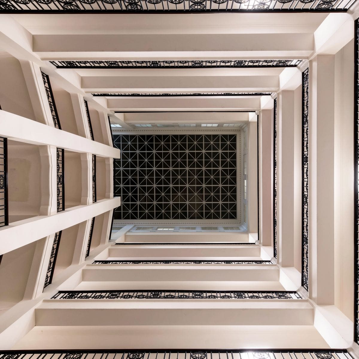 Atrium lumineux et moderne d'un immeuble avec plafond géométrique, symbole de parties communes de copropriété entretenues avec soin